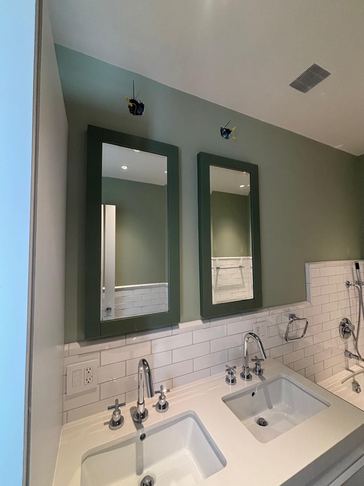 Sage green bathroom walls with painted mirror frames